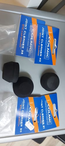 Recensent toont de zwarte Colmic Joint Cleaner-doppen en hun verpakkingen in verschillende maten.