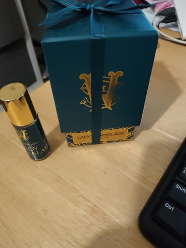 Customer's Lady Marmalade perfume bottle standing next to its elegant dark teal gift box.