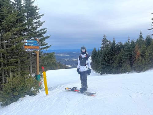 Reviewer wearing the Ink Dot Color-Block Insulated Snow Anorak while standing with a snowboard on a snowy mountain.