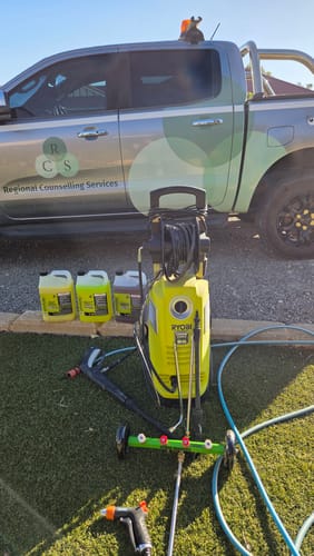 Customer's Triple Threat Care Package bottles displayed with a Ryobi pressure washer and attachments on a lawn.