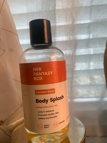 Customer's bottle of Body Splash Caramel Glaze body oil with its orange and white label.