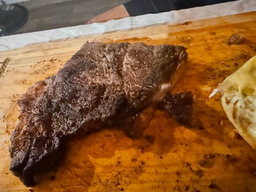 Primer plano del Diezmillo Steak asado de un cliente, reposando sobre una tabla de madera.