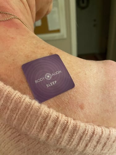 Reviewer with a purple Body Align Sleep Patch applied to their shoulder, peeking from under a sweater.