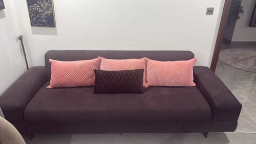 Customer's dark-colored Wagon 3 Seater Sofa in their living room, styled with three decorative pillows.