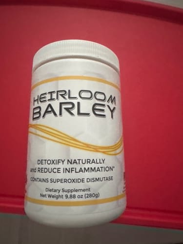 Customer's white jar of Heirloom Barley dietary supplement sitting on a red surface.
