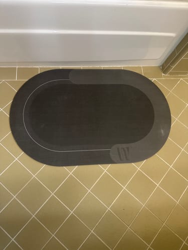 Customer's gray Magic Mat on a tiled bathroom floor, showing a visible scuff mark on the surface.