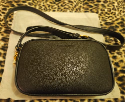 Reviewer's black Bianca Crossbody Bag with the matching strap, shown resting on a leopard-print surface.