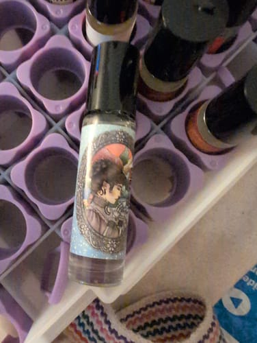 Reviewer's Winter Gothic perfume rollerball with an illustrated label, standing in a purple organizer tray.