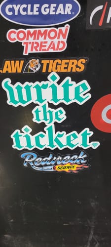 Customer's teal 'Write The Ticket' decal applied to a black toolbox among other stickers.
