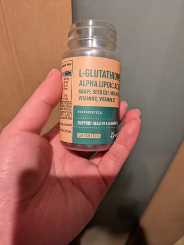 レビューアーが、L-グルタチオンのサプリメントボトルを手に持っている様子。