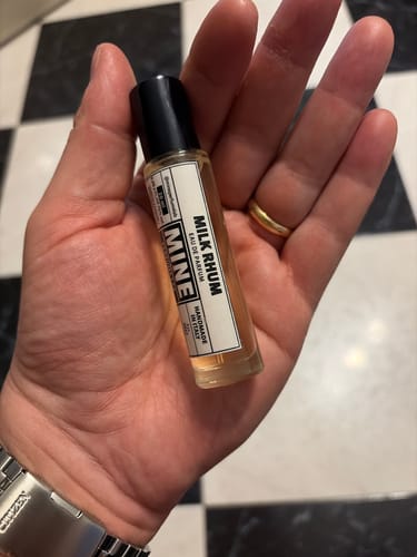 Cliente che tiene in mano la piccola boccetta roll-on del profumo MILK RHUM.