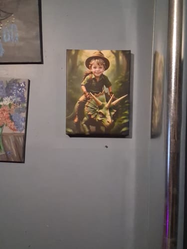Customer's 'The Dinosaur' personalized portrait of a smiling child riding a dinosaur, shown as a canvas print on a wall.