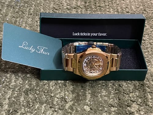 Customer's gold Lucky Fours® Skeleton watch displayed in its open green presentation box.