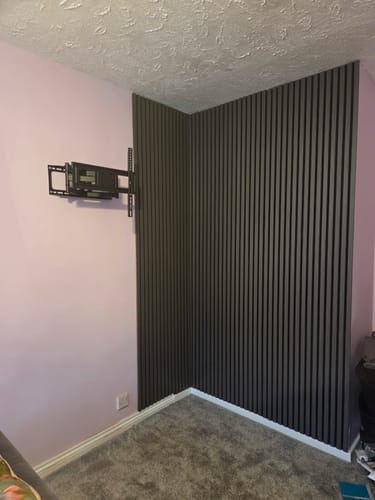 Customer's dark grey Premium Acoustic Wall Panels installed in the corner of a room next to a TV mount.
