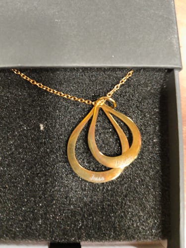 Reviewer's gold Celestial necklace with two engraved teardrop pendants resting in a black gift box.