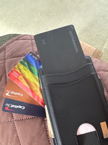 Customer's black SPOTMINDERS Tracking Card placed in a wallet sleeve alongside other cards.