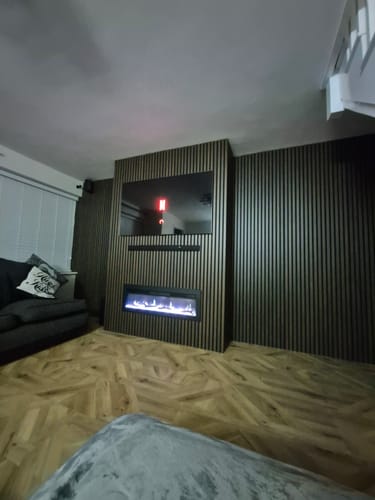 Customer's media wall featuring walnut Premium Acoustic Wall Panels with a mounted TV and electric fireplace.