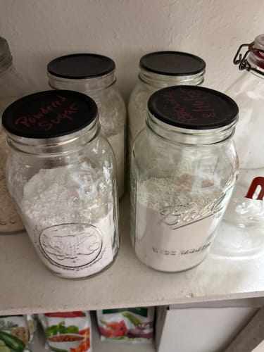 Customer's pantry showing several glass mason jars of dry goods with airtight black lids.