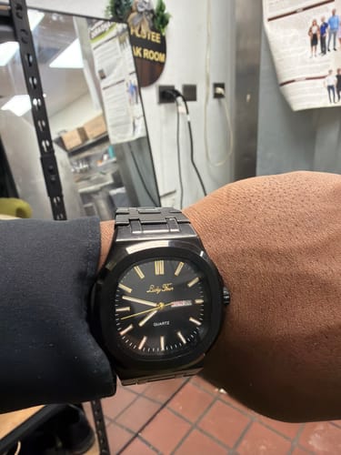 Reviewer wearing a sleek black watch with gold accents on their wrist.