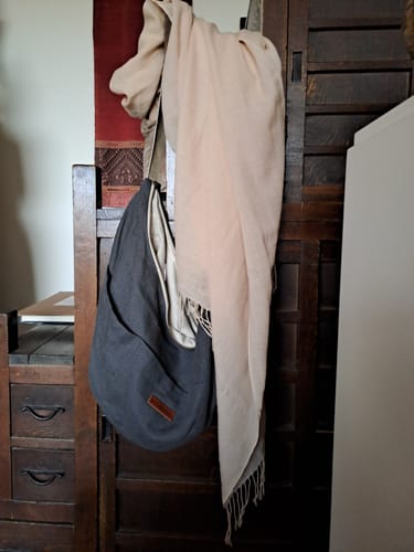 Avis d'un client : le sac Pia en lin gris suspendu sur un meuble en bois.