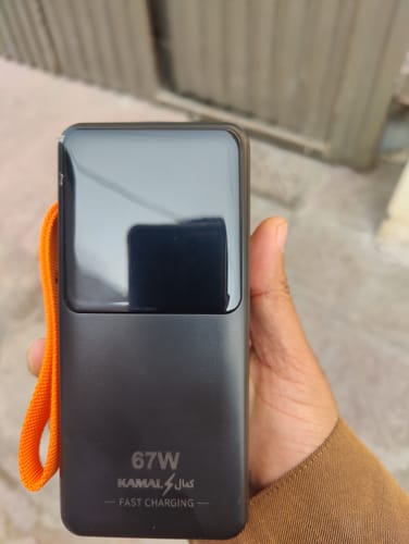 Customer holding the black 67W Powerbank KPB-041, showing its matte finish and attached orange wrist strap.
