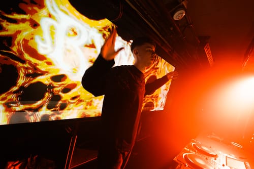 Reviewer in the black long-sleeved t-shirt at a music event with dramatic red and yellow lights.