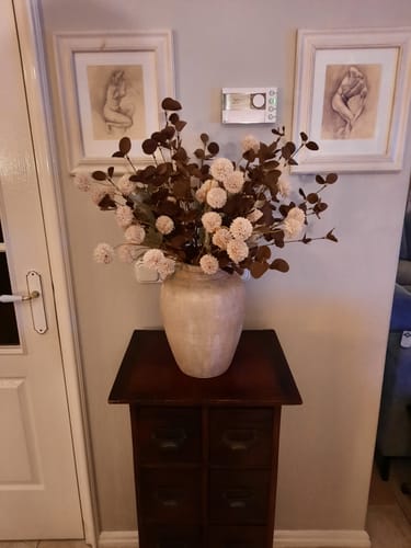 Recensent toont het samengestelde boeket Crème Mix, gearrangeerd in een grote vaas op een donkerhouten bijzettafel.