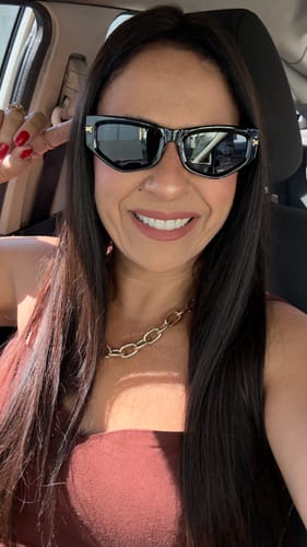 Cliente sorrindo e usando os Óculos Troia pretos dentro de um carro.