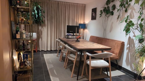 Beoordelaar toont de beige Nordic eetkamerstoelen aan een grote eettafel in een sfeervolle kamer.
