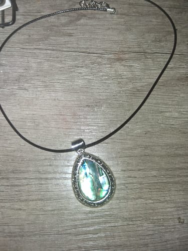 Customer's spiritual protection necklace from the AuraBloom Subscription Box laid out on a wooden surface.