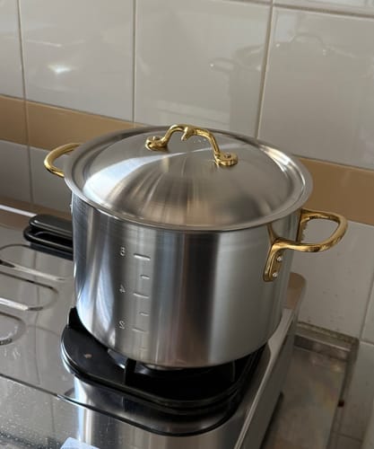 顧客的中尾不鏽鋼雙耳半身湯鍋放在瓦斯爐上，鍋身有容量刻度，並配有亮眼的黃銅手柄。
