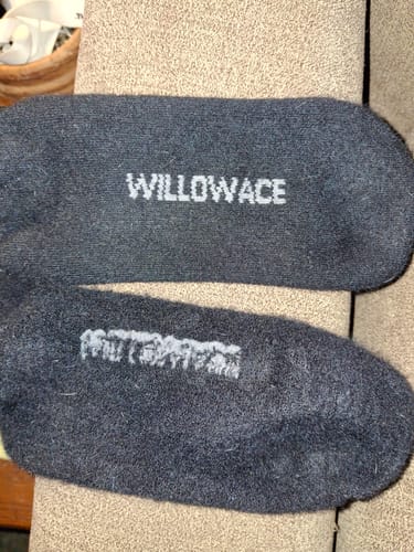 Customer's photo comparing the soles of two black Men's Alpaca Socks, one showing more wear than the other.