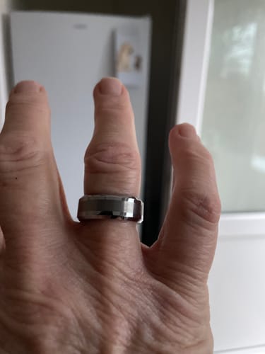 Customer's hand wearing the Alaric ring, showing its polished, beveled-edge design.