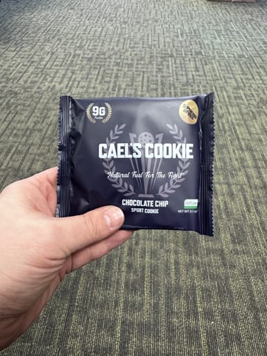 Customer holding the dark blue package for a Cael’s Cookie, showing the Chocolate Chip flavor.