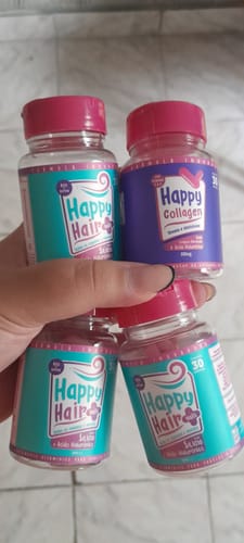 Cliente segurando três potes de Happy Hair e um pote de Happy Collagen recebidos no kit.