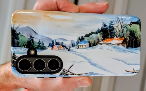 Customer holding a custom Galaxy S25 FE case with a detailed print of a watercolor winter landscape.