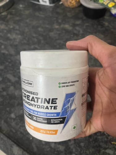 Reviewer holding a white tub of Wellcore Pure Micronised Creatine Monohydrate.