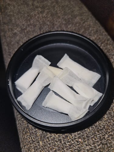 Reviewer's open black tin showing several soft Sweet Nectar Nicotine Pouches.