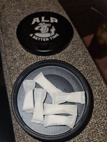 Customer's open black Metal Travel Tin with white pouches inside and the logo lid placed next to it.