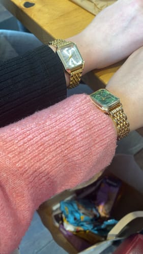 Customer and a friend showing their matching gold CLAIRE DE MAINS watches, one with a light dial and one with a green dial.