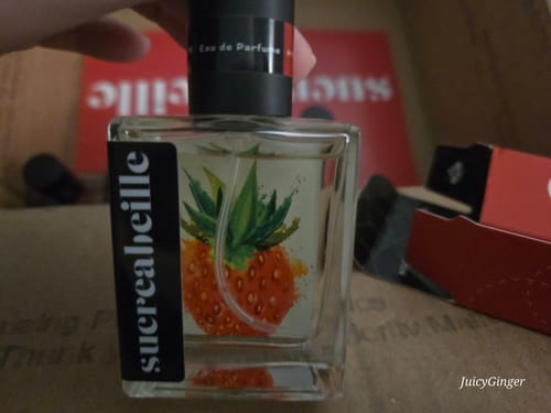 Customer holding the square glass Strawberry Bliss perfume bottle, showing its artistic strawberry label.