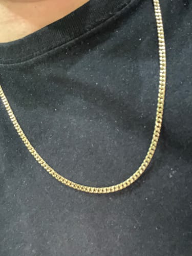 Primer plano de un reseñador usando la Cadena Miami Cuban Oro de 3mm sobre una camiseta negra.