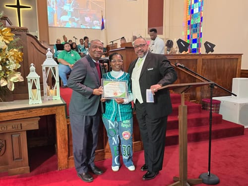 Reviewer in a custom green baseball jersey receiving a certificate on a church stage.