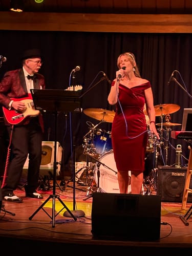 Reviewer singing on stage in the wine red velvet bodycon vintage dress.