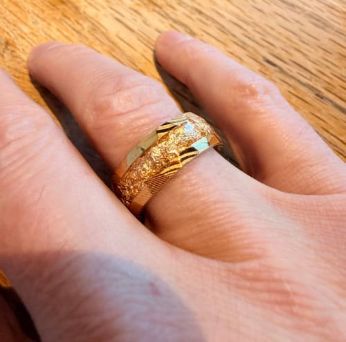 Reviewer's hand wearing the Doreon ring, showing its textured gold inlay and carved band.