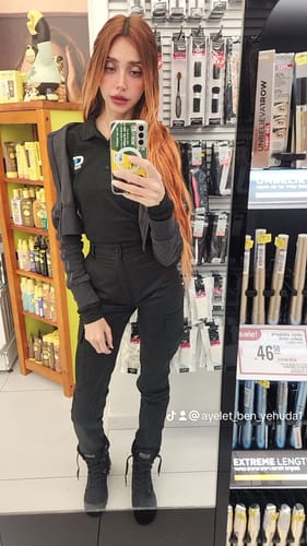 לקוחה בתמונת מראה באורך מלא, נועלת נעלי Baggy שחורות כחלק מתלבושת שחורה.