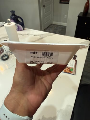 Reviewer holding the side of the Bangin' Breakfast Burrito container, showing the product label.