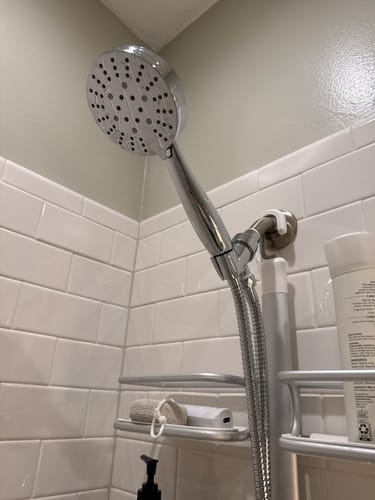 Customer's shiny, chrome Handheld Shower Head Set installed in a white tiled shower.