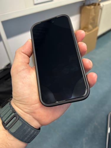 Kunde hält ein iPhone, bei dem sich die Schutzfolie an den Rändern durch die Handyhülle abhebt.