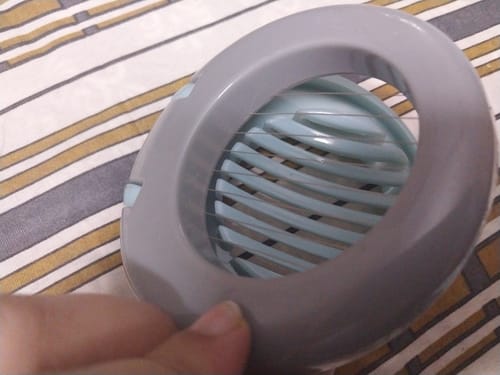 Customer holding the closed grey and light blue Egg Slicer, showing the thin cutting wires inside.